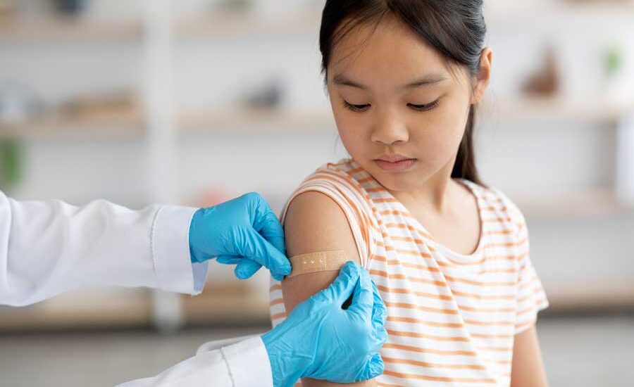 Young girl getting a band-aid on her arm after having a shot.