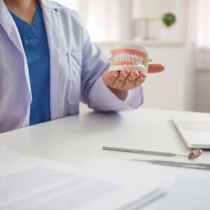 Doctor holding fake mouth teeth in his hands.