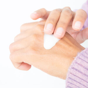 Hands of a woman putting lotion on her hand.
